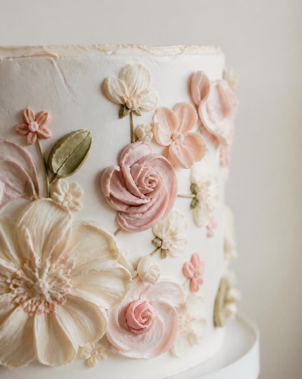 Close das flores de buttercream feitas à mão na lateral de um bolo